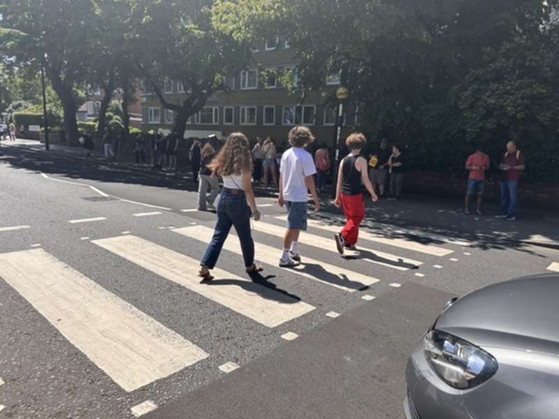 Teens visiting the famous Beatles Abbey Road, walking across