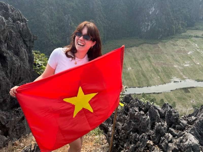 TEFL teacher exploring Ninh Binh, Vietnam while holding the Vietnamese flag during a weekend adventure.