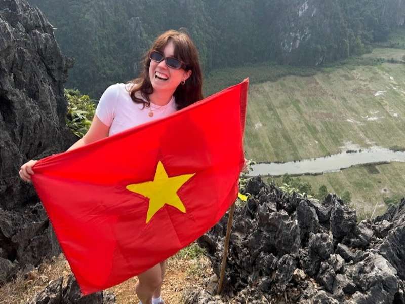 TEFL teacher exploring Ninh Binh, Vietnam while holding the Vietnamese flag during a weekend adventure.