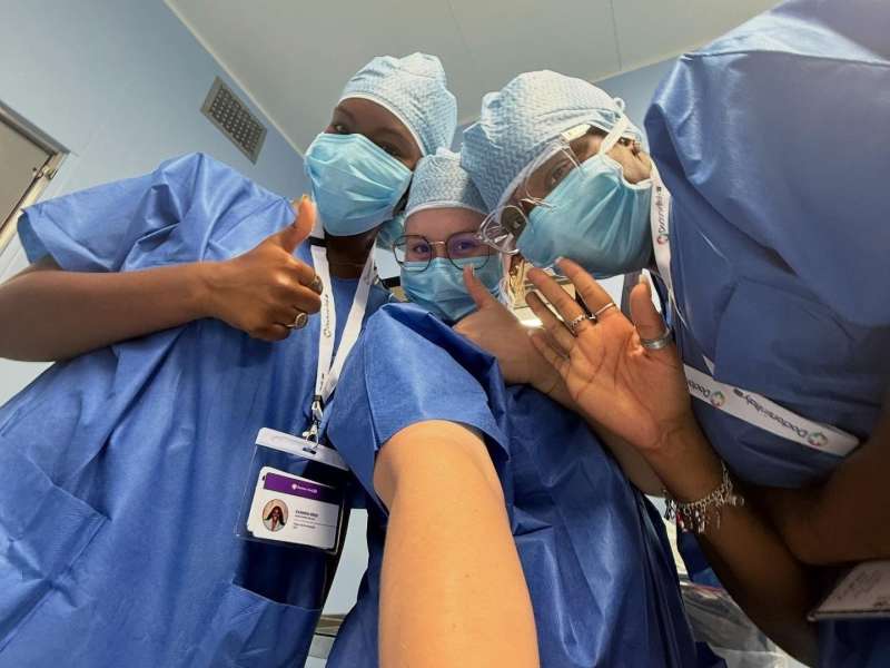Three fellows in their scrubs and masks on taking a quick selfie.