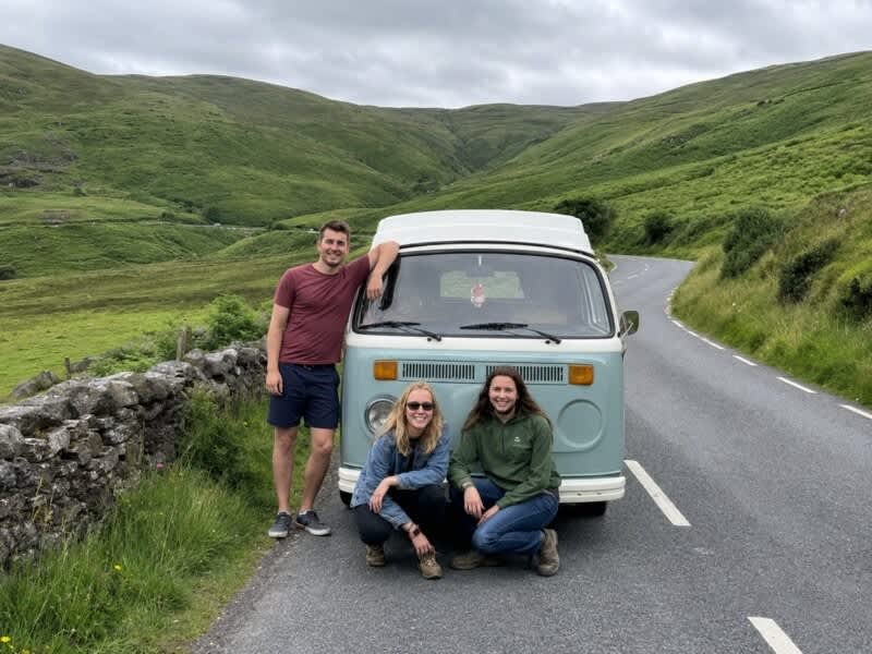 Three friends beside a campervan in the Irish countryside