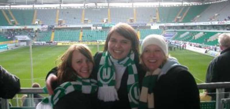 Three happy girls with a stadium on the background
