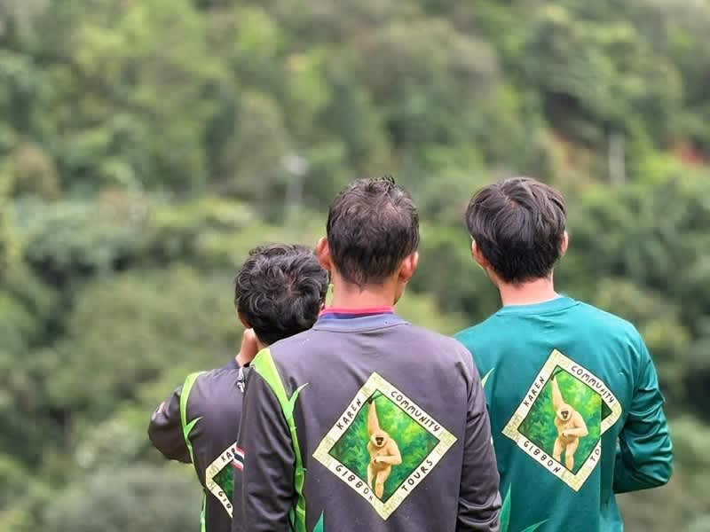 Three Karen guides in Community Gibbon Tours shirts on a hillside