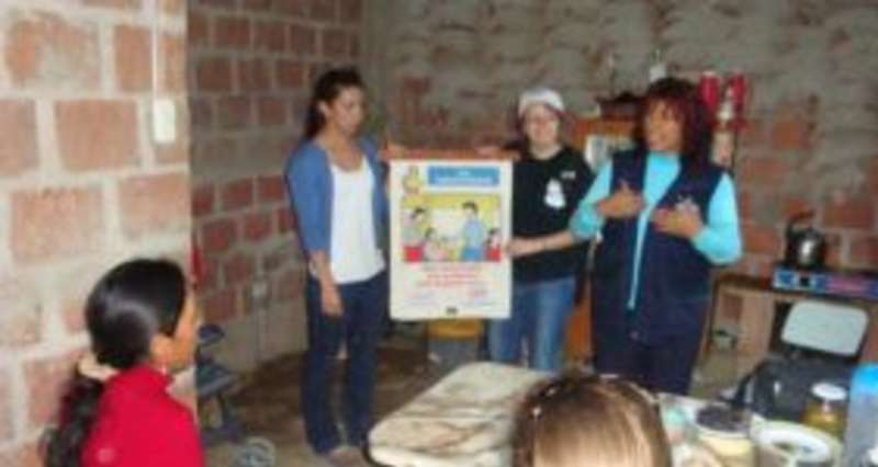 Three people conduct a presentation in a sparsely furnished room with brick walls