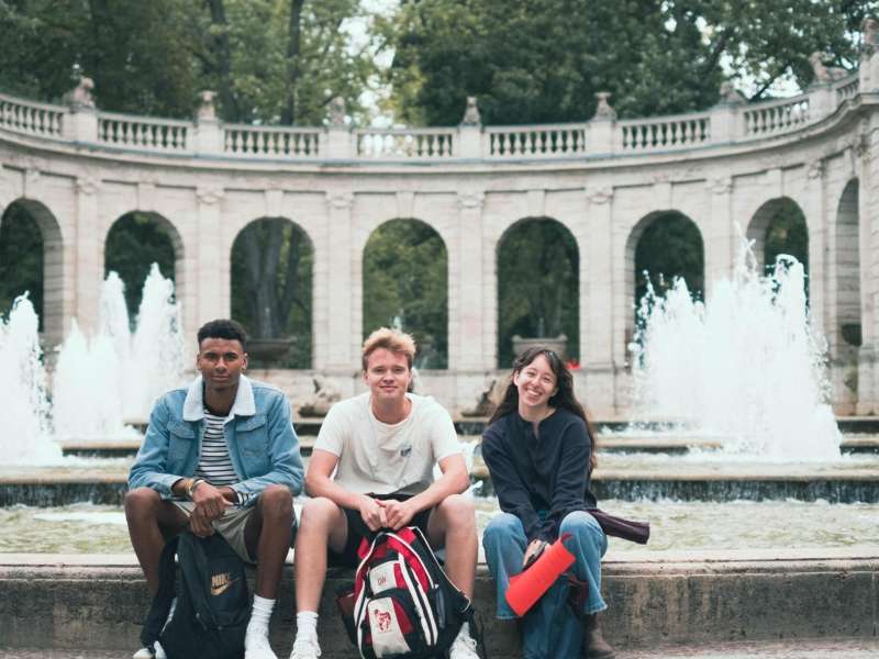 Three students sit by a fountain in Berlin.