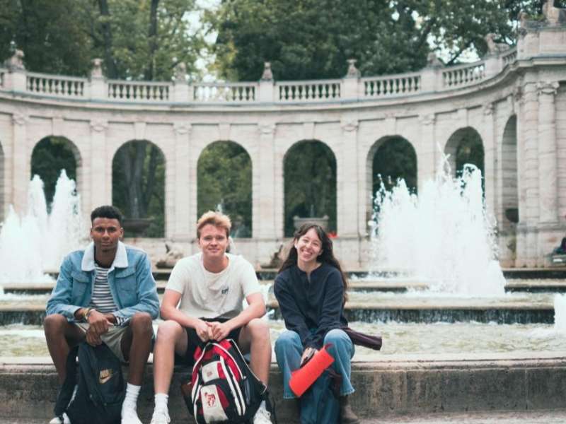 Three students sit near a campus in between classes in Berlin, Germany.
