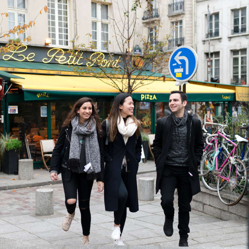 Three students walk past a cafe.