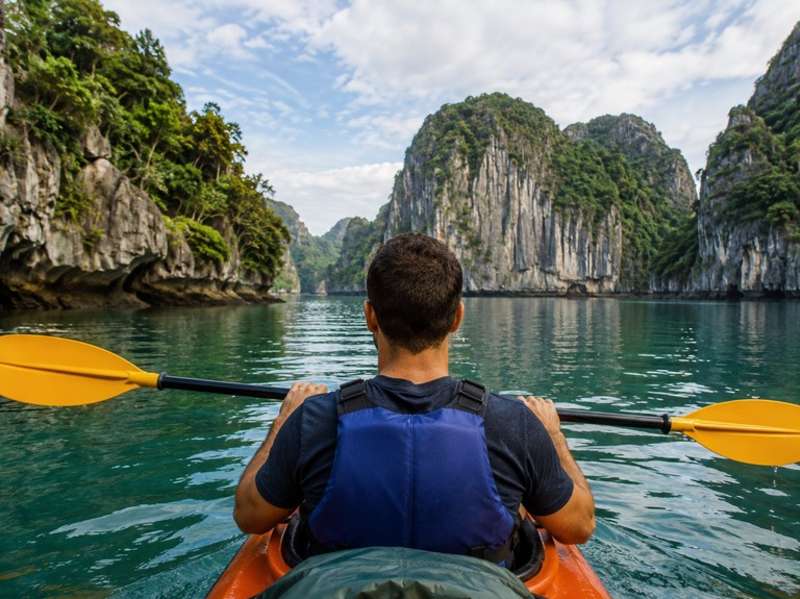 Traveller kayaking between limestone cliffs in Vietnam