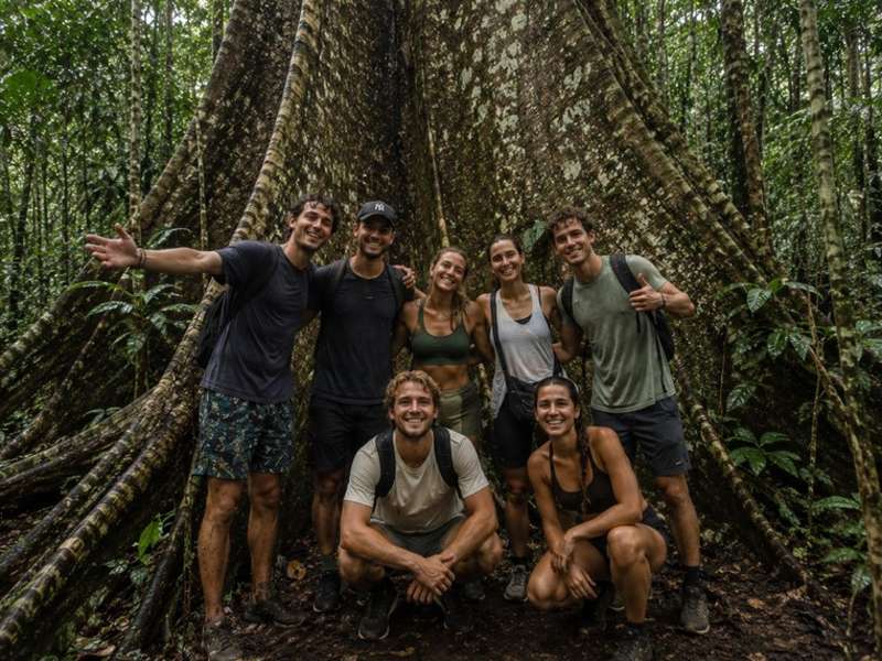 Travellers beneath a giant rainforest tree in Thailand