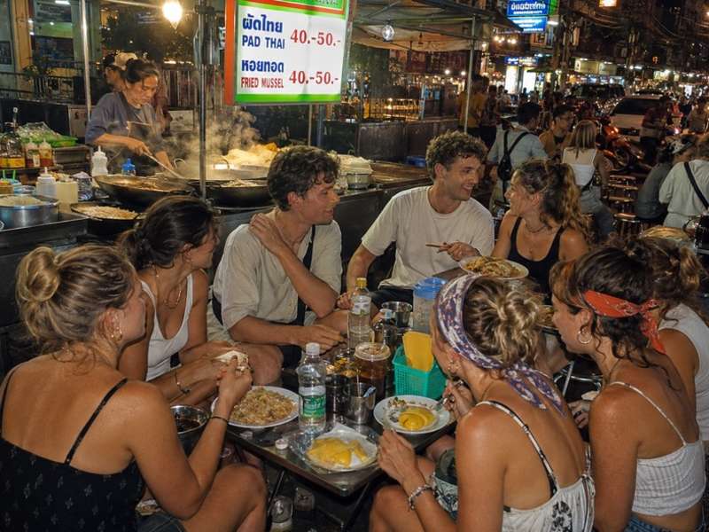 Travellers eating Pad Thai at a Bangkok street stall