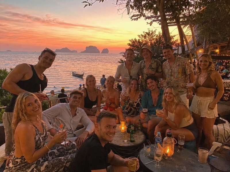 Travellers enjoying sunset drinks beside the Thai coast