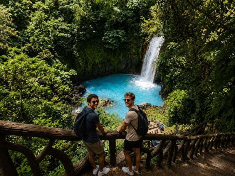 Travellers overlooking a bright blue Costa Rican waterfall