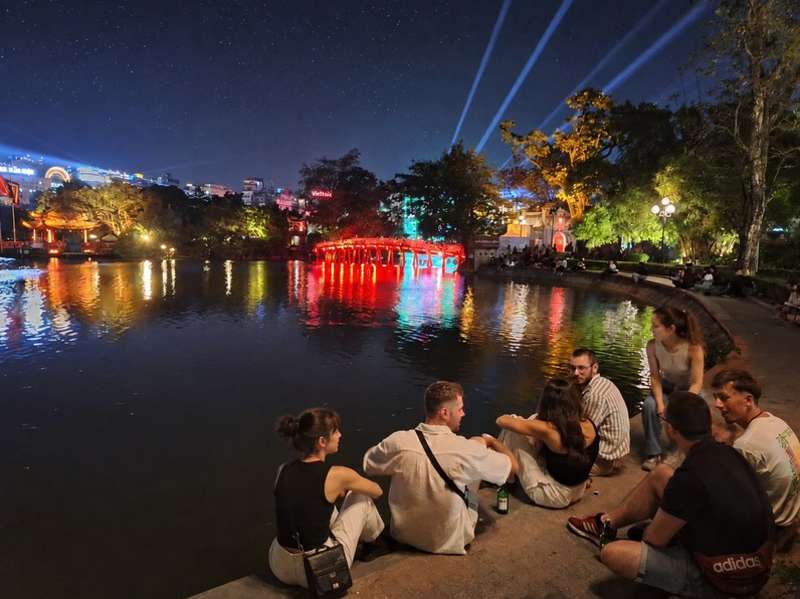 Travellers relaxing beside Hoan Kiem Lake in Hanoi at night