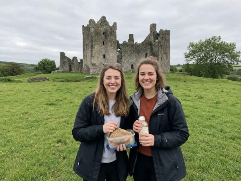Two friends enjoying lunch beside a historic Irish castle
