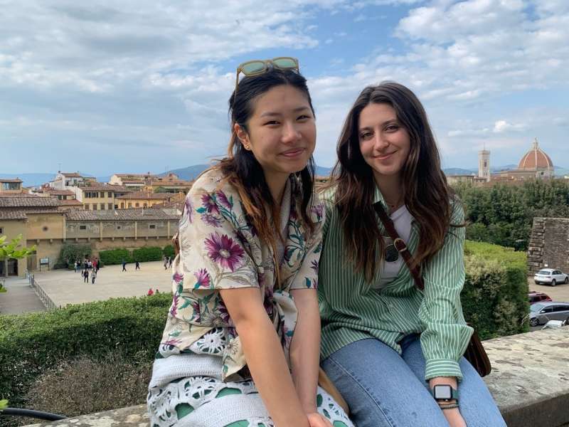 Two friends sitting on a ledge at an overlook of Florence, Italy