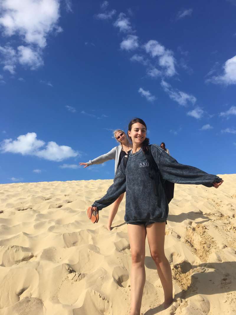 two girls pose for a photo in the sand