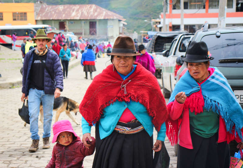 Two Indigenous women and child at the market in Simiatug Ecuador  with traditional hats and dress