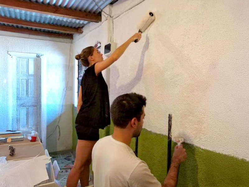 Two IVHQ Volunteers repainting a green wall white