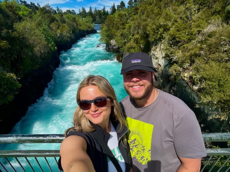 Two people standing on a bridge with a river in the background