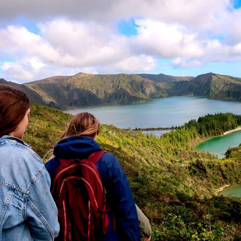 Two students hiking down to a lake from a mountaintop