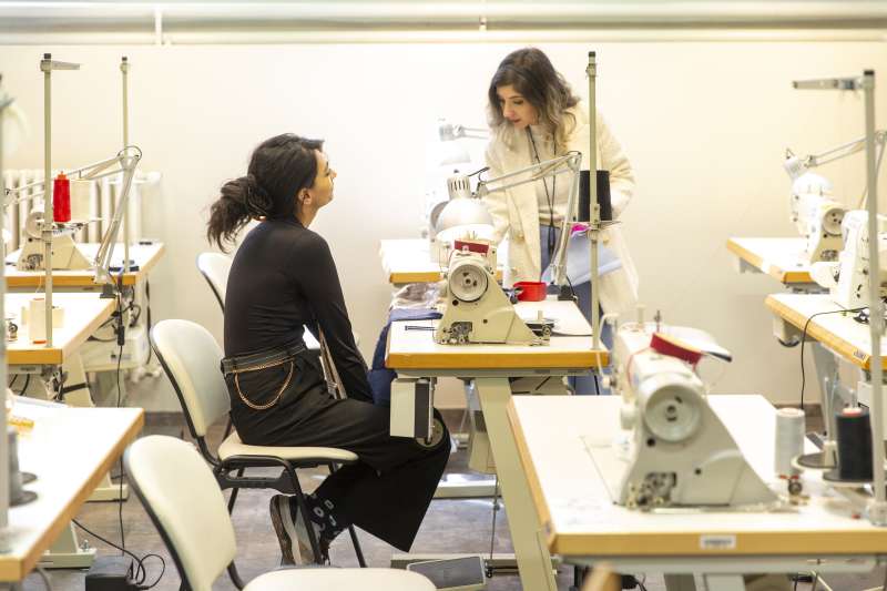 Two students in a fashion design lab with sewing machines