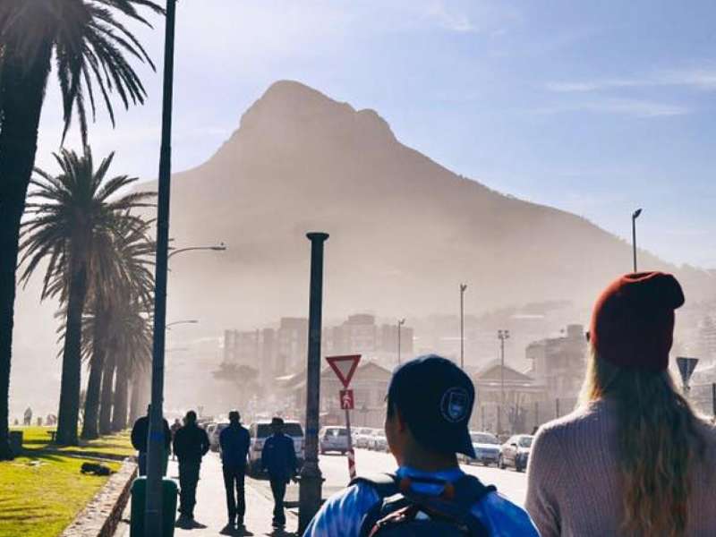 Two students in front of a scenic promenade near the ocean in Cape Town