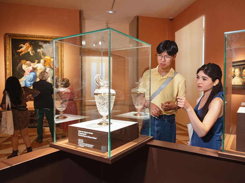 Two students look at a glass vase on exhibit in a museum