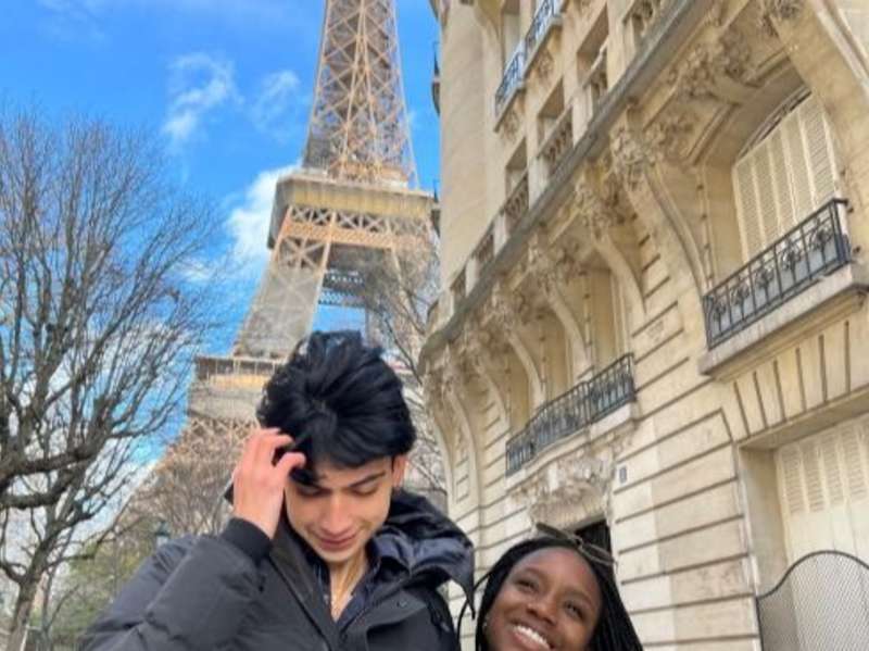 Two students pose by the eiffel tower.