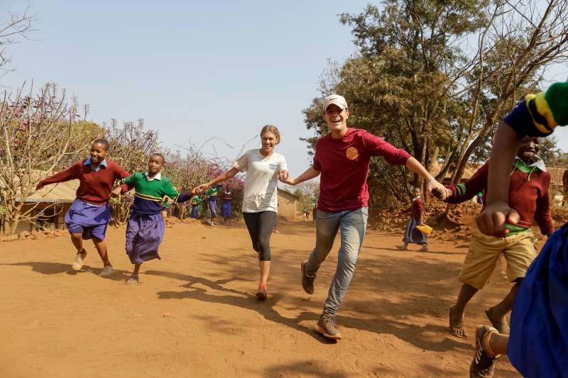 Two teens running with school children in Tanzania