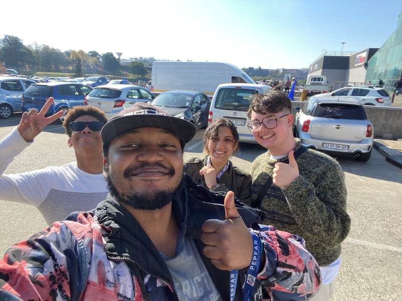 Two volunteers and two members of staff smile into the camera and give an enthusiastic thumbs up