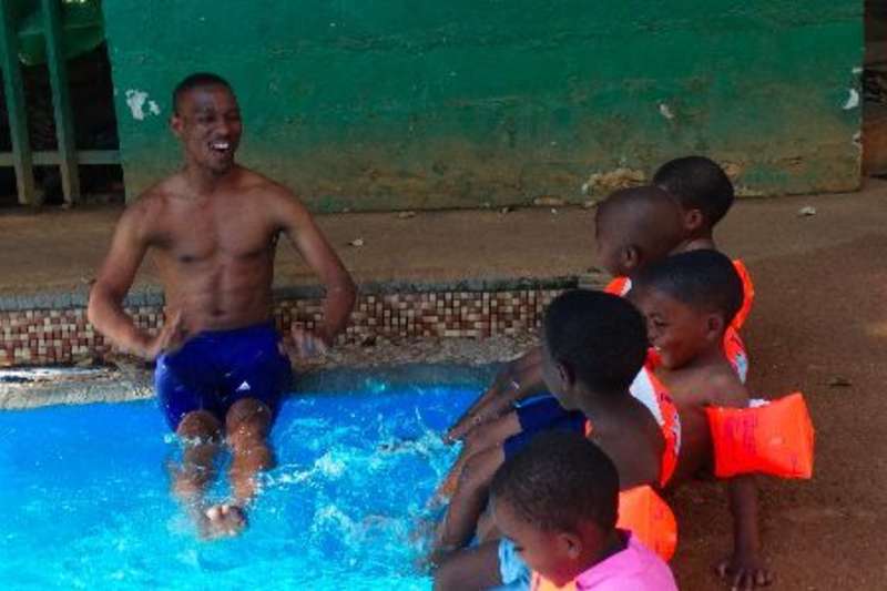 volunteer and children practice kicking in the pool