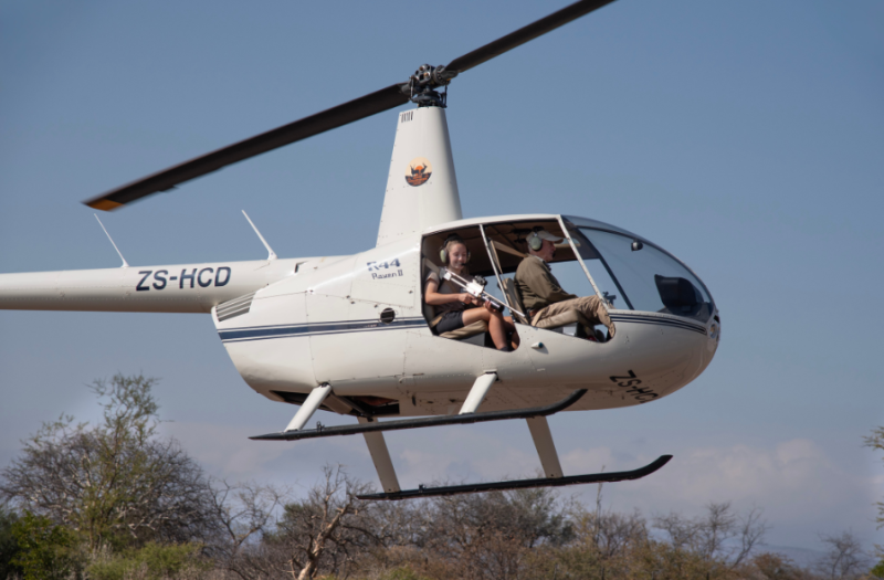 Volunteer in helicopter practising their darting skills as part of the veterinary darting course