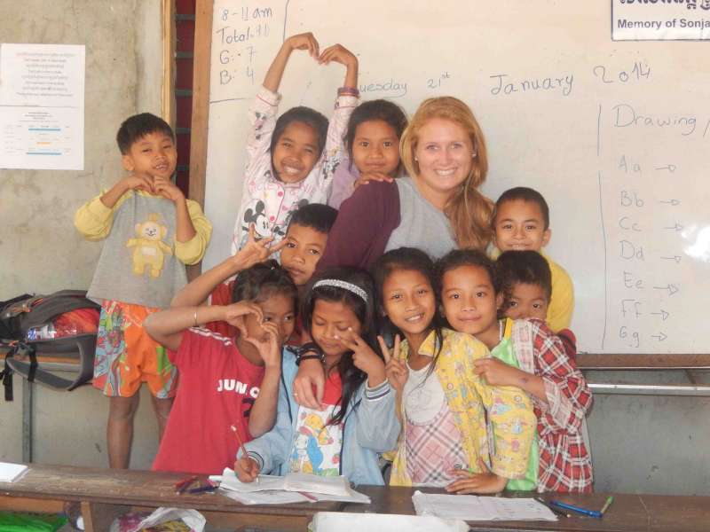 Kid doing a heart sign with teacher volunteer and other children