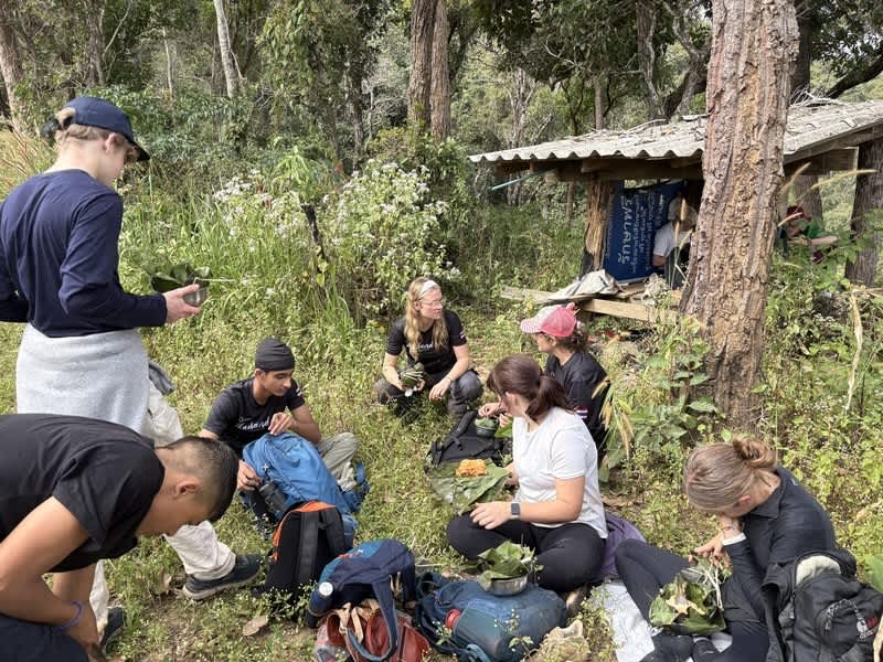 Volunteers and local team eating together in the forest