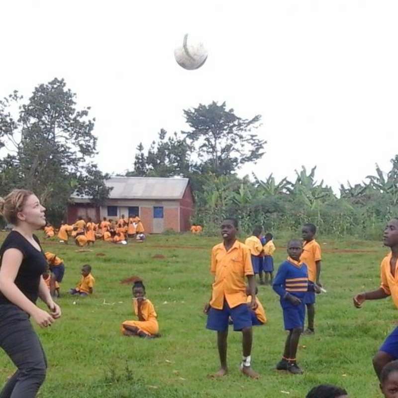 Volunteer playing football with school children in Uganda, Africa