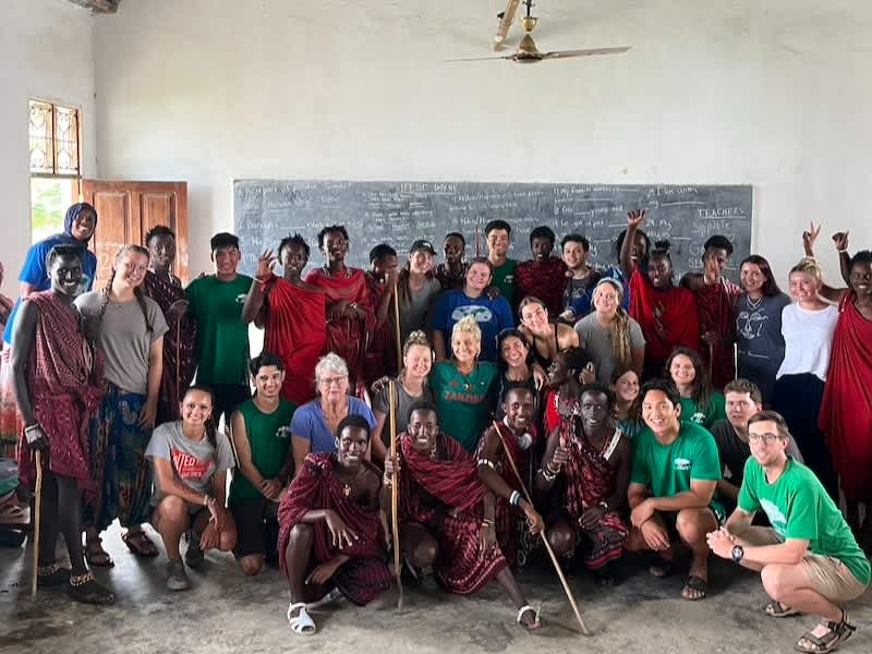 Volunteers with local students in rural Tanzania teaching English