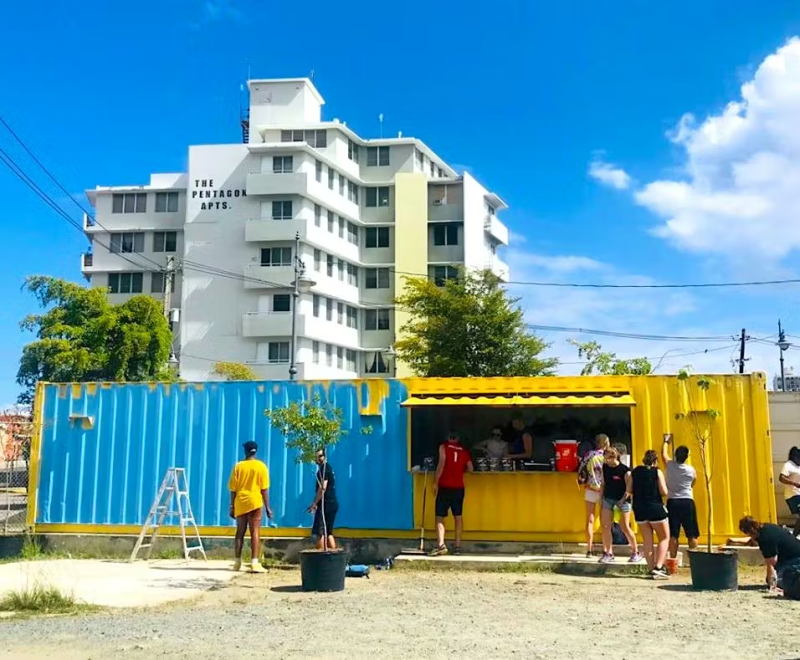 Volunteers working around colorful shipping containers being converted