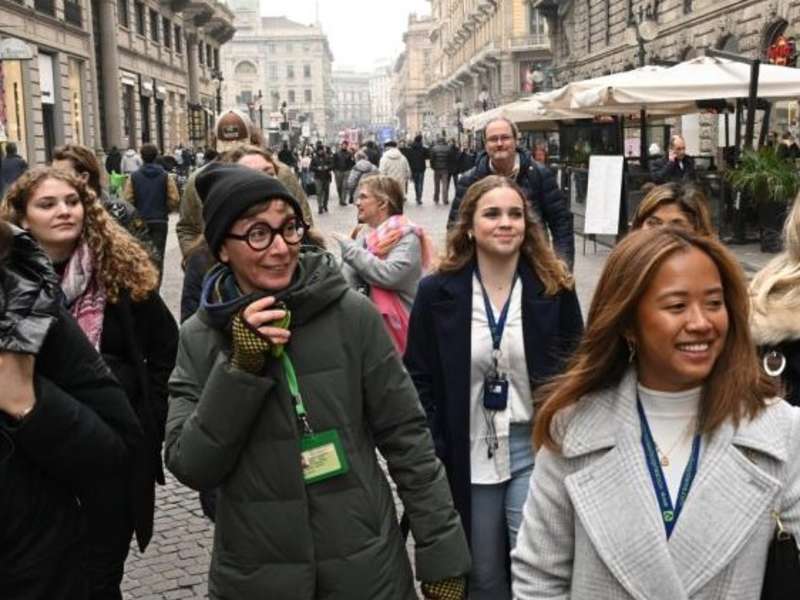 warmly dressed students and a professor walk through the streets of milan