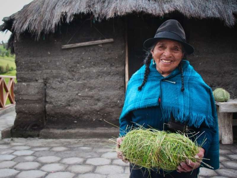 weaver-holding-grass-bundle-adobe-house-ecuador