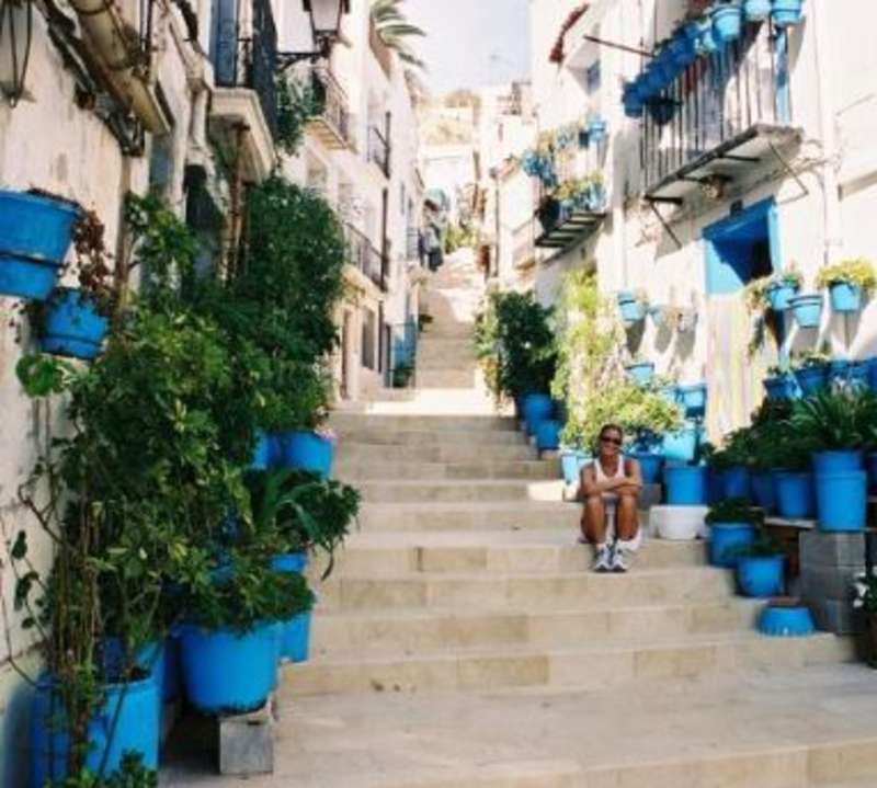 Woman sitting on stairs with plant-decorated house